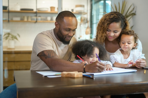 Heureux parent afro-américain jouant et dessinant avec ses filles à la maison