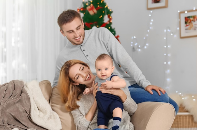 Heureux parents avec bébé dans une chambre décorée pour Noël