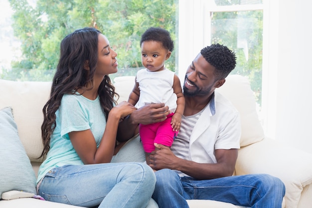 Heureux parents avec bébé fille sur le canapé