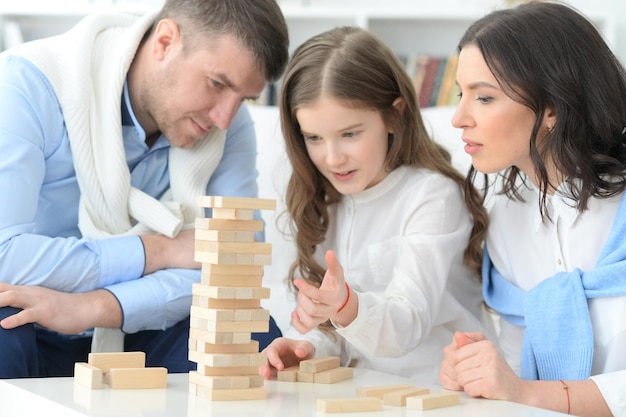 Heureux parents et fille jouant avec des blocs de bois dans la chambre