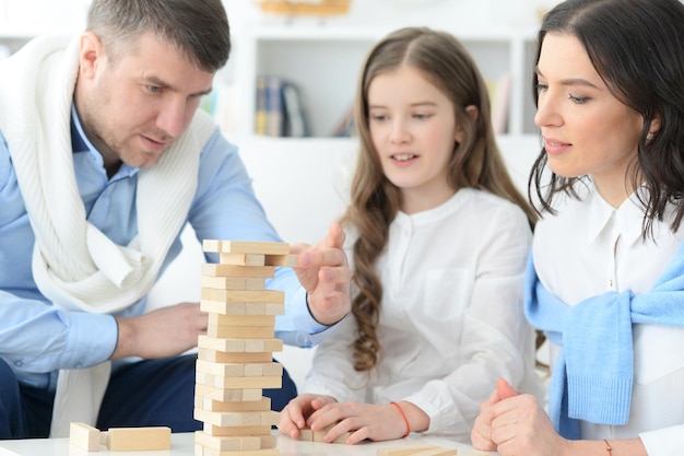 Heureux parents et fille jouant avec des blocs de bois dans la chambre