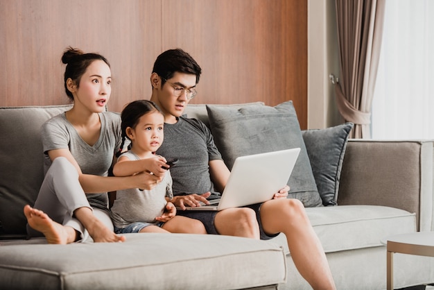 Photo heureux parents avec fille utilisant un ordinateur portable dans le salon