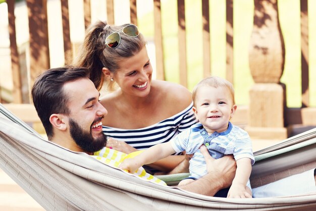 Heureux parents jouant avec leur petit garçon dans un hamac à l'extérieur