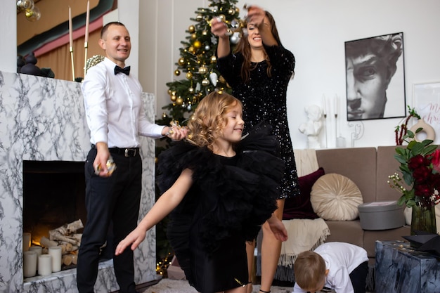 Heureux parents et leurs enfants heureux jouant avec des confettis à Noël à la maison