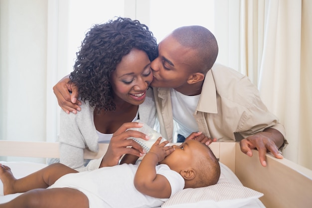 Heureux parents nourrissent leur petit garçon dans son berceau