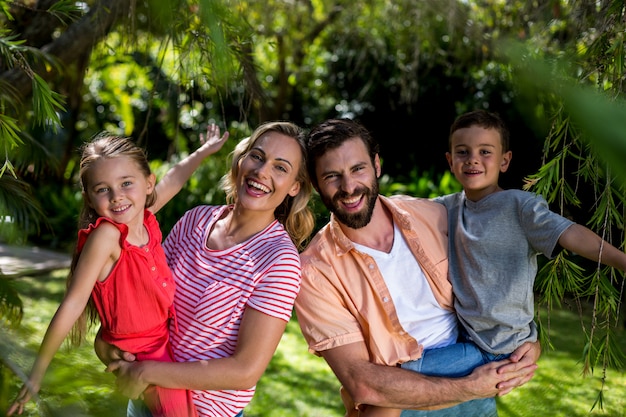 Heureux parents portant des enfants souriants à yard