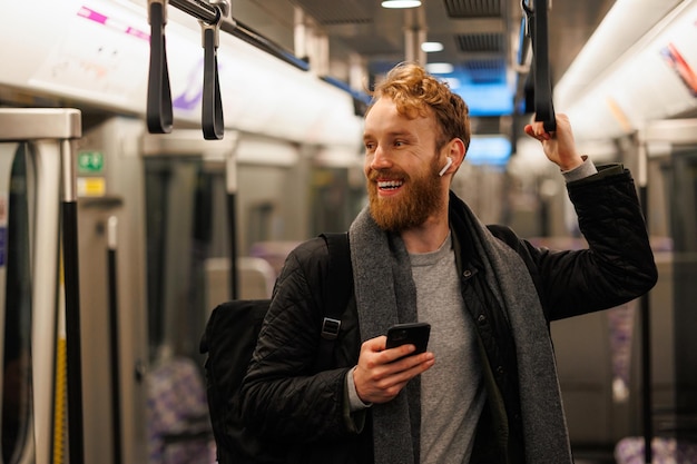 Heureux passager du métro masculin est debout dans le train