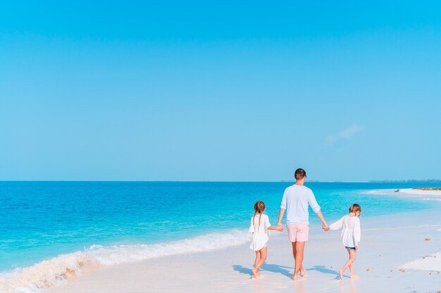 Heureux père et adorables petits enfants sur la plage tropicale en s'amusant. Vacances en famille