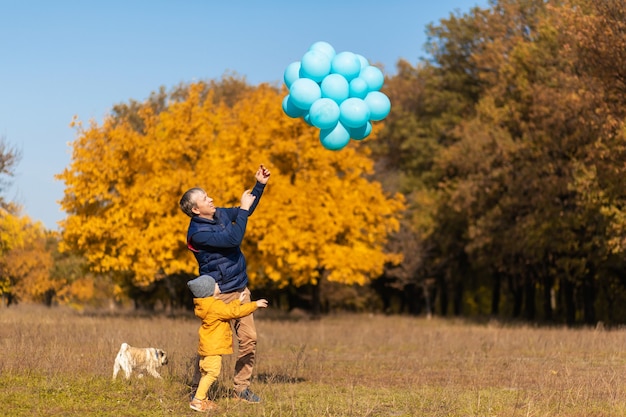 Heureux père aime passer la journée avec son enfant dans le parc en automne. Jouer avec des ballons