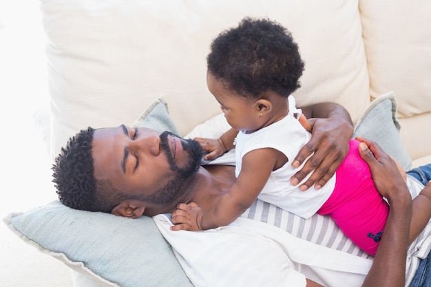 Heureux père avec bébé fille sur le canapé