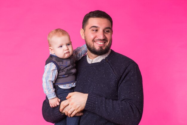 Heureux père avec un bébé fils isolé sur rose.