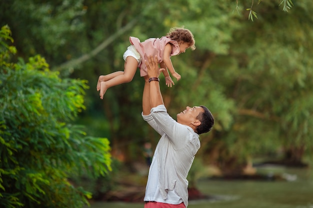 heureux père bronzé mâle pour une promenade avec son enfant. papa vomit sa petite fille, ils jouent et rient