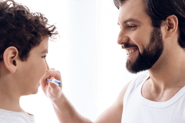 Heureux père brosse les dents du jeune fils avec la brosse à dents.