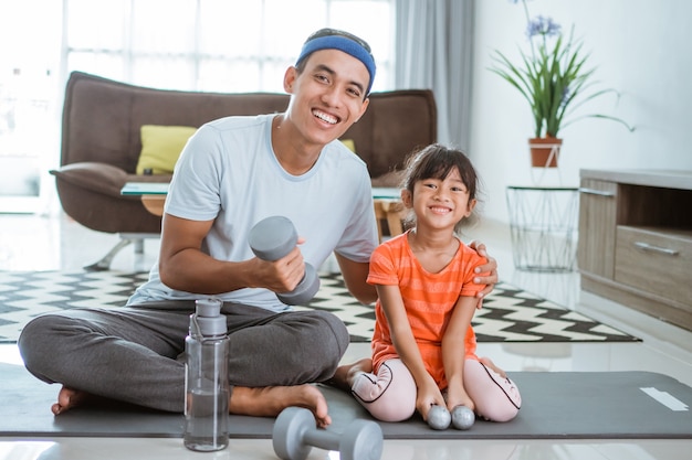 Heureux père et enfant faisant de l'exercice ensemble. portrait d'entraînement familial sain à la maison. homme et sa fille sport