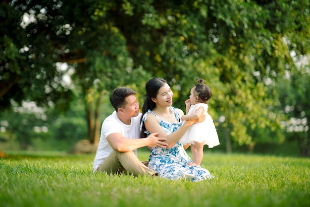 Heureux père de famille asiatique mère et petite fille enfant jouant dans le parc en profitant de la belle nature au coucher du soleil Concept de vacances en famille heureuses