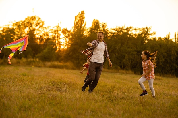 heureux père de famille et enfant fille courir avec un cerf-volant sur le pré