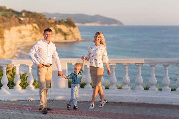 Heureux père de famille mère bébé fils marche avec plaisir le long du bord du surf de la mer au coucher du soleil sur la mer Noire