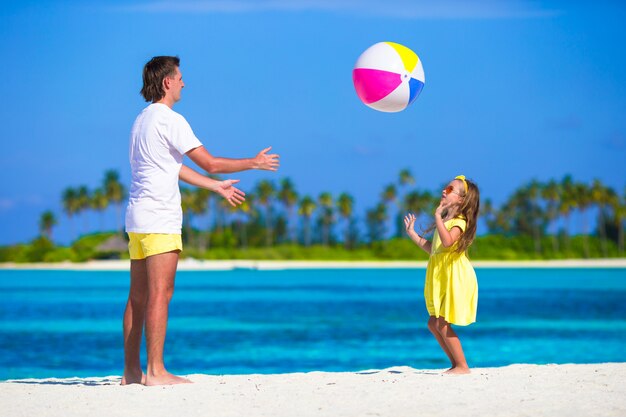 Heureux père et fille courir sur la plage avec ballon s'amuser ensemble