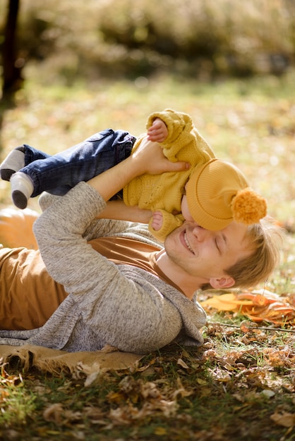 Heureux père et fille dans le parc automne couché sur des feuilles jaunes