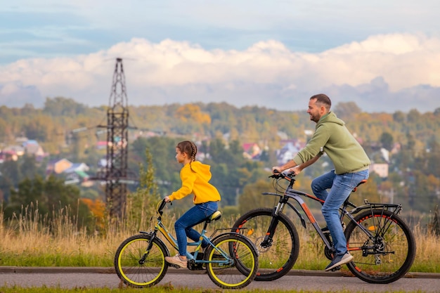 Heureux père et fille font du vélo dans la nature en automne