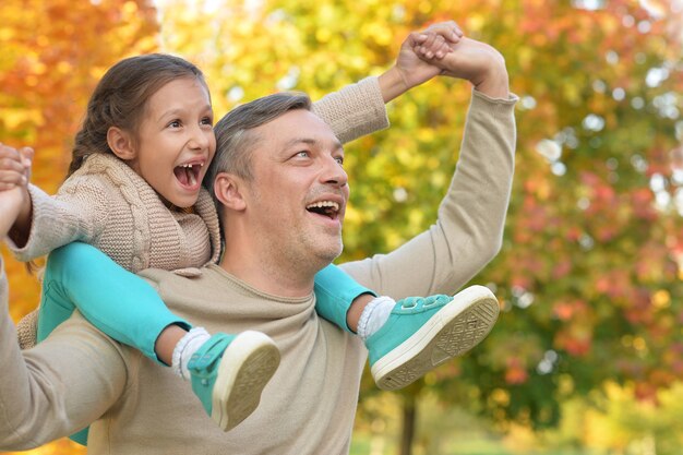 Heureux père et fille posant en plein air en automne
