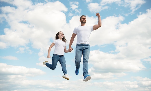 Heureux père et fille sautent dans le ciel enfance heureuse