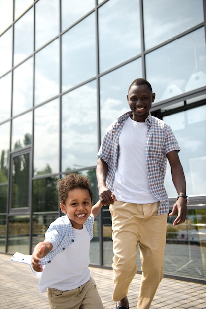 Heureux père et fils afro-américains se tenant la main et courant