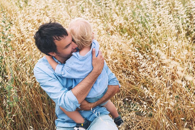 Heureux père et fils Antécédents familiaux Papa et son petit garçon mignon jouant et étreignant sur un champ de blé avec des meules de foin le jour d'été sur la nature à l'extérieur Concept de confiance confiance amour