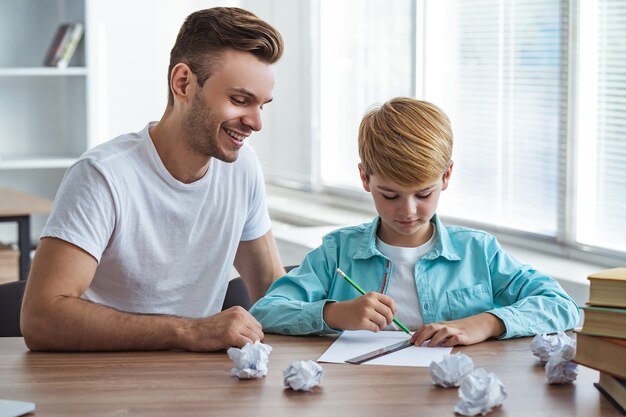 L'heureux père et un fils assis au bureau et dessinant sur le papier