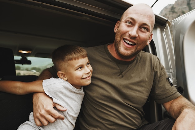 Heureux père et fils assis dans le coffre de la voiture