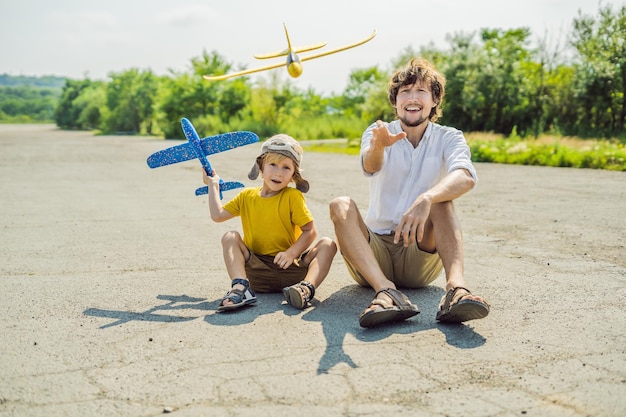 Heureux père et fils jouant avec un avion jouet sur fond de piste ancienne Voyager avec le concept d'enfants