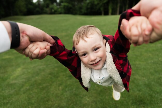 Heureux père et fils jouant ensemble dans le parc. papa tient les mains de son fils. temps de repos de l'enfant avec le père. un petit enfant se promène dans la nature avec un jeune papa