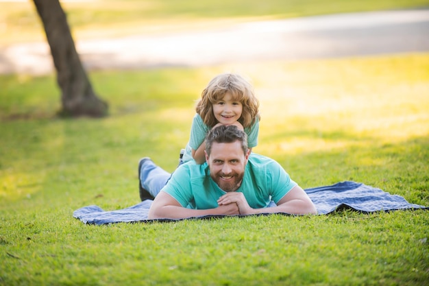 Heureux père et fils profitant de l'heure d'été en vacances dans un parc ensoleillé