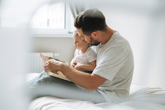 Heureux père jeune homme et petite fille petite fille s'amusant à lire un livre dans la chambre des enfants à la maison