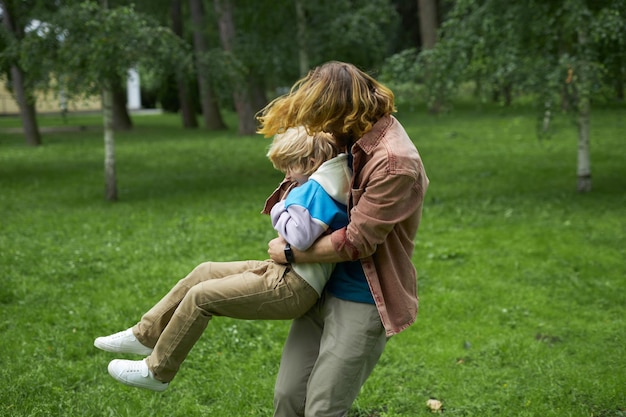 Heureux père jouant avec un petit enfant dans le parc et tourbillonnant en rond