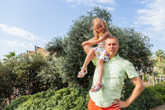 Heureux père joue et porte sa fille sur ses épaules un jour d'été