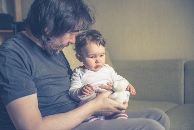 Heureux père joue avec son bébé sur le canapé à la maison