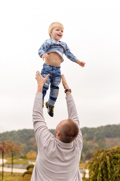 Heureux père joyeux s'amusant jette en l'air l'enfant. Famille, voyage, vacances, concept de fête des pères.