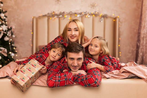 Heureux père de mère de famille et enfants le matin de Noël au lit en pyjama