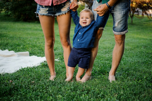 Photo heureux père et mère tenant un petit garçon avec et marcher sur l'herbe