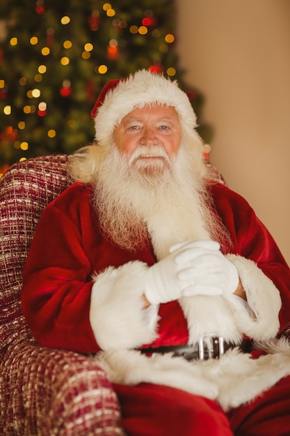 Heureux père Noël relaxant sur le fauteuil