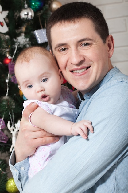 Heureux père avec petit bébé près de l'arbre de Noël