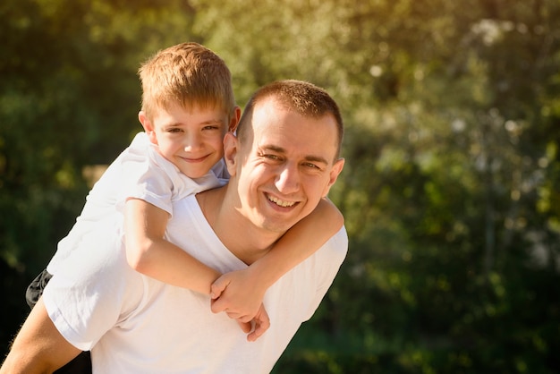 Heureux Père Avec Petit Fils Sur Le Dos à L'extérieur