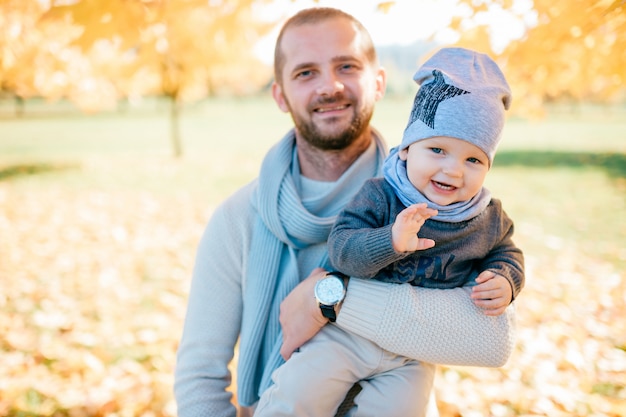 Heureux père posant avec son enfant élégant dans le parc automne