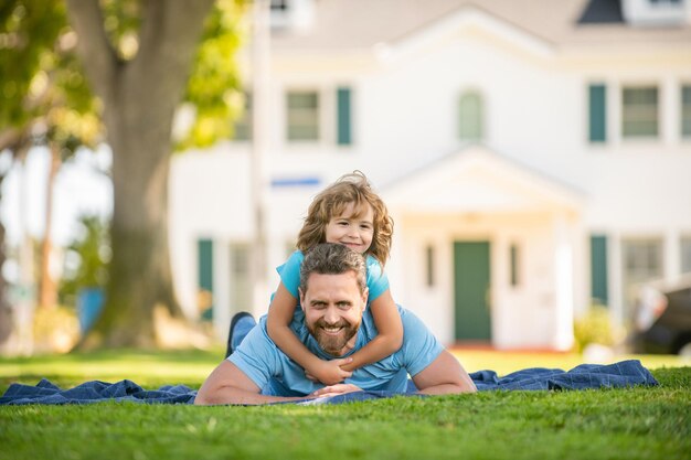 Heureux père s'amusant avec un enfant se détendre ensemble sur des amis de l'herbe du parc verdoyant