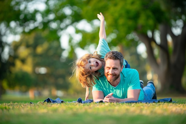 Heureux père avec sa famille de fils jouant avec un enfant allongé dans l'herbe sur un pré