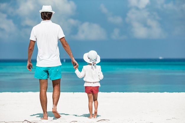 Heureux père et son adorable petite fille à la plage tropicale marchant ensemble