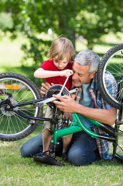 Heureux père et son fils en train de réparer un vélo