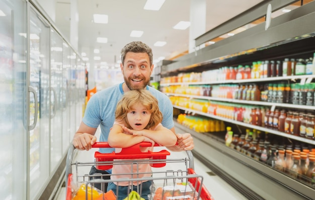 Heureux père souriant et fils enfant avec panier acheter de la nourriture à l'épicerie ou au supermarché