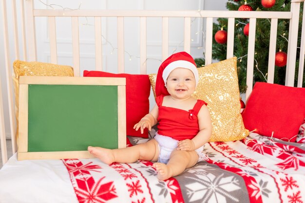 Heureux petit bébé dans un bonnet de Noel assis dans un berceau